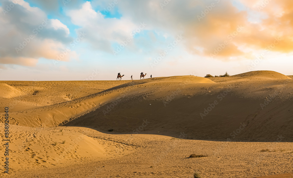 Sand dunes of Thar desert Jaisalmer with view of tourist enjoying camel safari at Rajasthan India Sand dunes of Thar desert Jaisalmer with view of tourist enjoying camel safari at Rajasthan India
