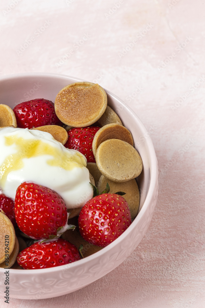 Homemade cereals mini pancake with yogurt, honey and strawberries on colorful background. Homemade cereals mini pancake with yogurt, honey and strawberries on colorful background.