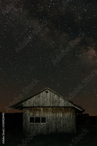 Small old wooden house on the background of the starry night. Starry night