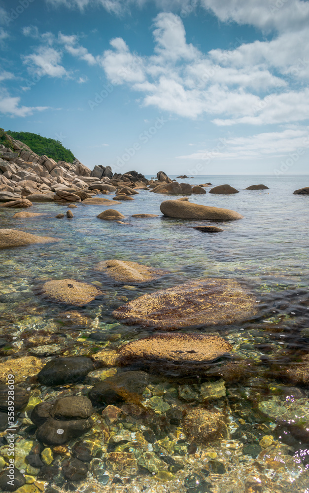 View of the seashore with large stones and marine life under water