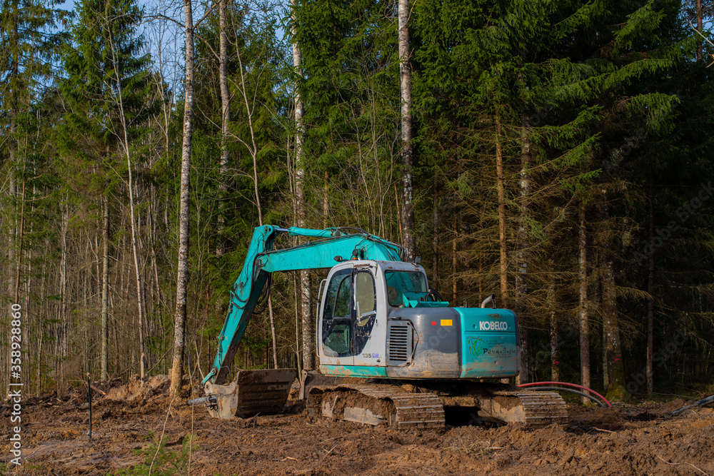 Aespa / Estonia - March 26 2020: Deforestation of forest. Excavator used to dig up tree-stumps and roots after the forest was removed