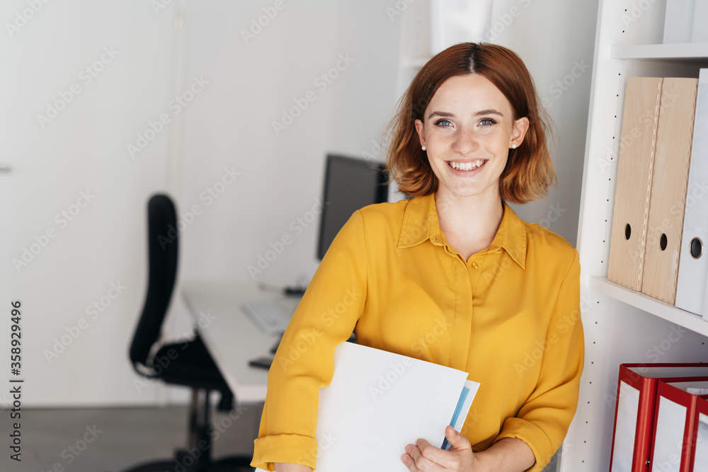 © contrastwerkstatt - Relaxed friendly businesswoman holding a binder