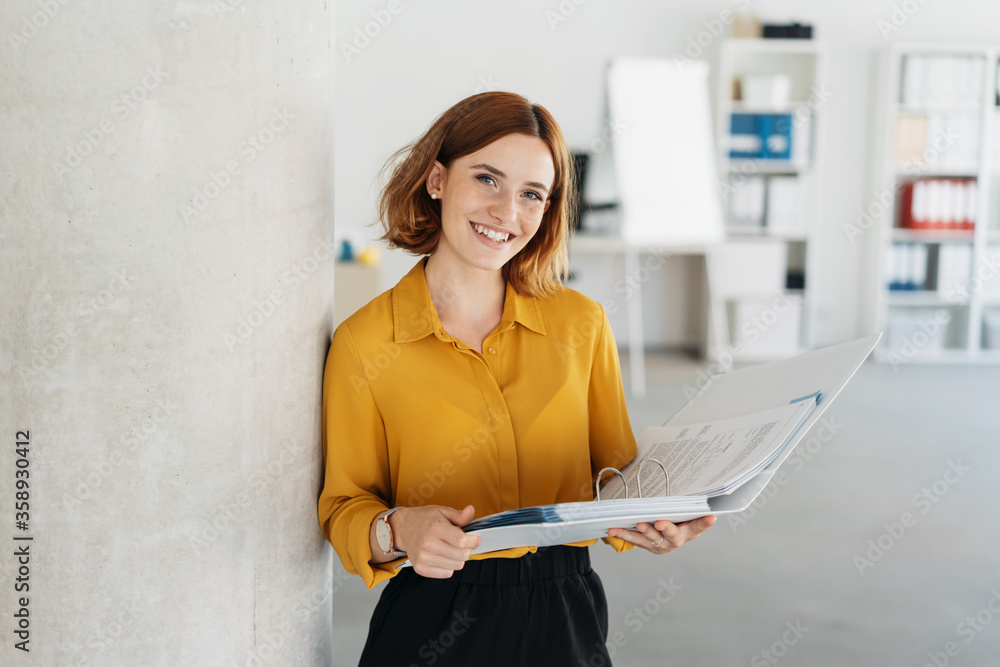 Attractive young office worker holding large file - obrazy, fototapety, plakaty 