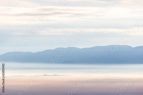 Fog filling a valley in Umbria  Italy  at dawn  with layers of mountains and hills