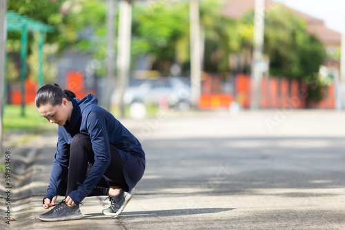 Active Asian woman tying shoe lace before running.