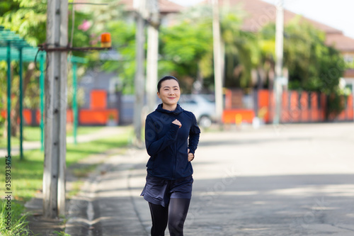 Portrait of Asian woman running at village park © chajamp