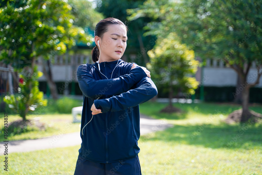 Fototapeta premium Portrait of Asian woman wearing earphones listening to music was sick with body pain at park.