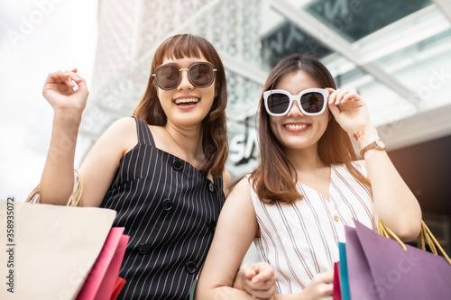 Asain woman in shopping. Happy woman with shopping bags enjoying in shopping.lifestyle concept.Smiling girl  holding colour paper bag.Friends walking in shopping mall © anon