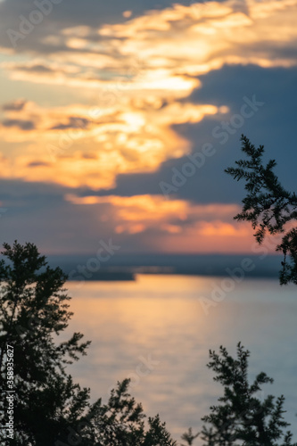 sunset with reflection over the river. Beautiful sunrise through spruce tree branches