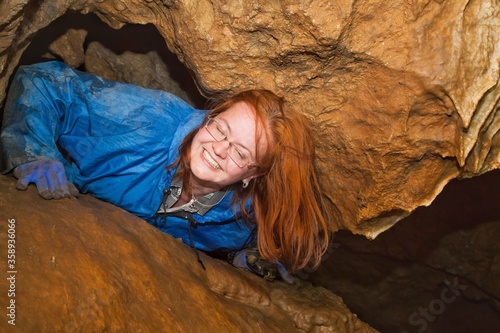 Red-haired girl-caver smiles in the cave. photo