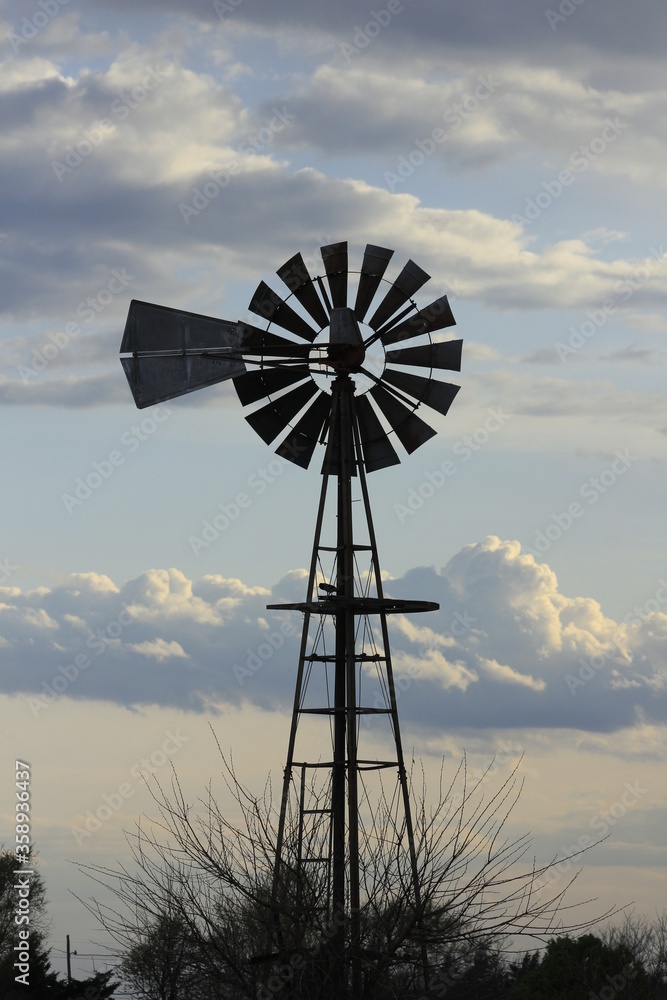 Kansas Country Windmill at Sunset with clouds and tree's north of Hutchinson Kansas USA. Kansas Country Windmill at Sunset with clouds and tree's north of Hutchinson Kansas USA.
