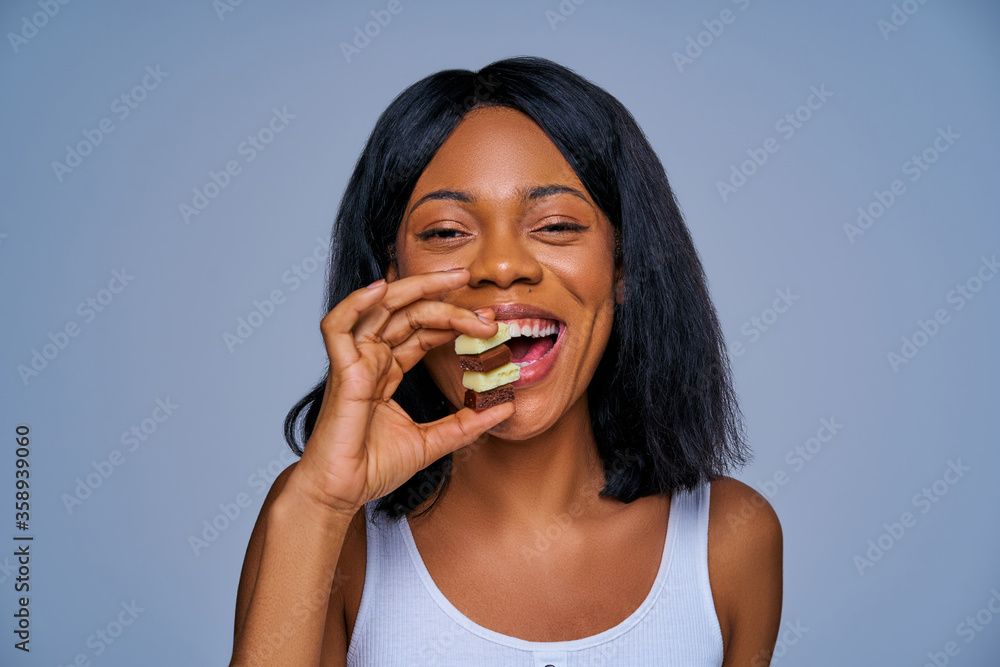 Thin woman with joy hold pile of white and black porous chocolate between fingers. Diet concept Thin woman with joy hold pile of white and black porous chocolate between fingers. Diet concept