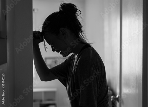 Fototapeta A sad woman crying and depressed in her room at home alone.