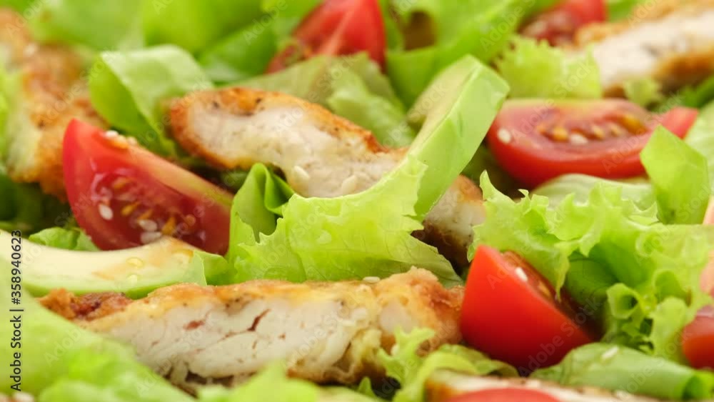 chicken salad with avocado, tomatoes, lettuce, sesame seeds rotating. Healthy salad with chicken