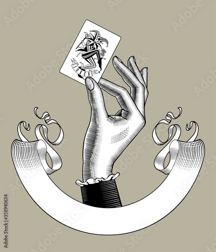 Engraved vintage drawing of a female hand holding Joker playing card and retro ribbon banner