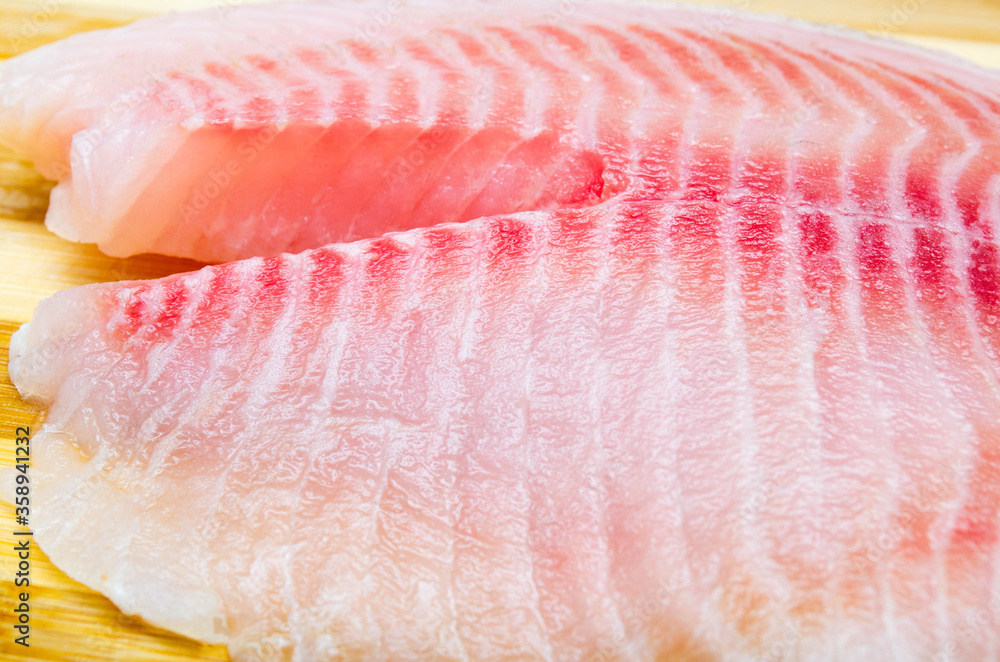 One filet of hare fish, rabbit fish on a cutting board in macro. Dorado ...