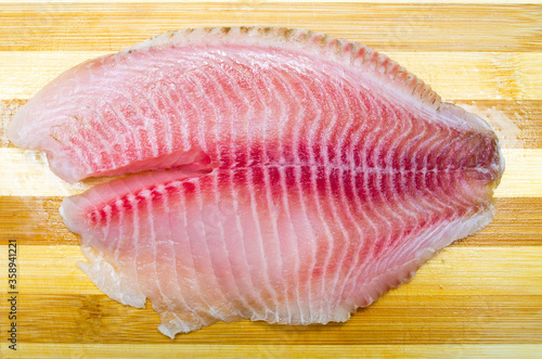 One filet of hare fish, rabbit fish on a cutting board in macro. Dorado fillet, telapia. Raw fish, seafood in macro. Top and side view. Large approximation of filet