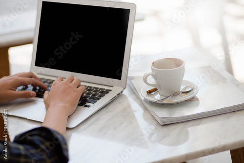 businesswoman working on laptop with cup of coffee on book in cafe.