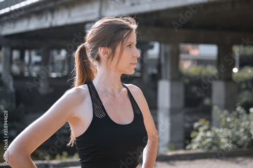 Young woman doing gymnastics on the street. Portrait of fit and sporty young woman doing stretching in city.