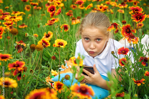 Girl with a mobile phone in nature .A happy child is relaxing outdoors in nature . Children use modern technologies for recreation, entertainment and education