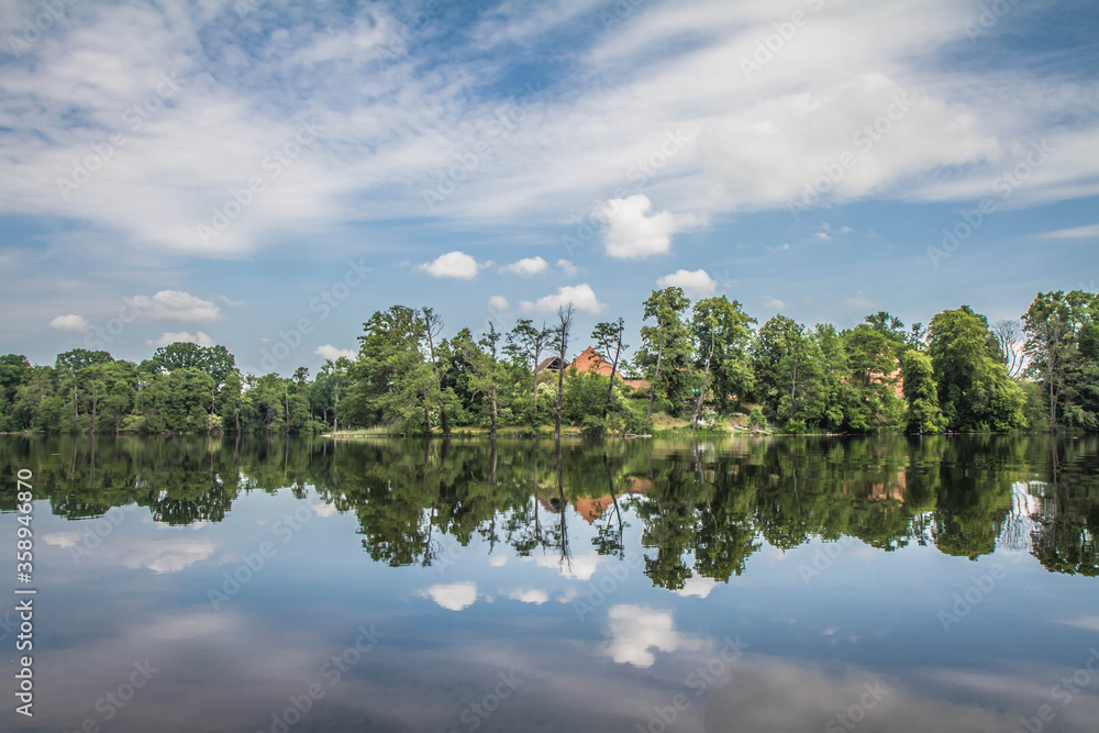 Fototapeta premium Lake, with forest around it, an some old damaged buildings seen in the distance