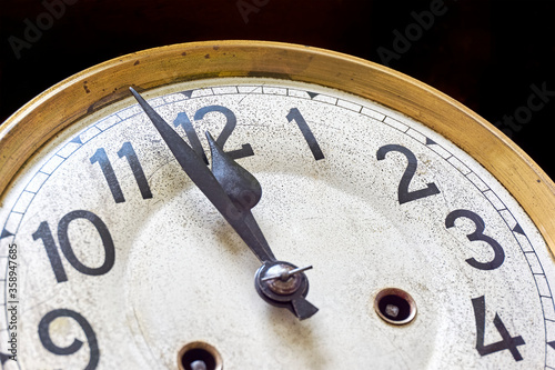 Old vintage clock shows 2 minutes to 12 o'clock against a black background. New year's eve or countdown concept. 