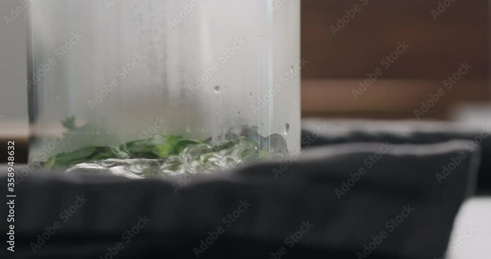 Slow motion pour black tea with thyme and mint with water in beaker glass closeup Slow motion pour black tea with thyme and mint with water in beaker glass closeup