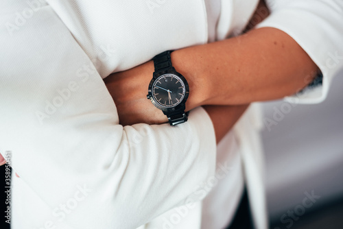 folded arms of a woman in a white shirt with a black watch