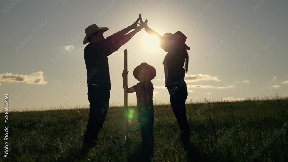 Teamwork. Happy family father, mother and son dream of their own home represent the symbol of future housing. Happy parents hold their hands over the child's head at sunset. Teamwork. Happy family father, mother and son dream of their own home represent the symbol of future housing. Happy parents hold their hands over the child's head at sunset.