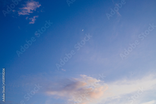 picturesque view of endless blue summer sky with clouds and moon