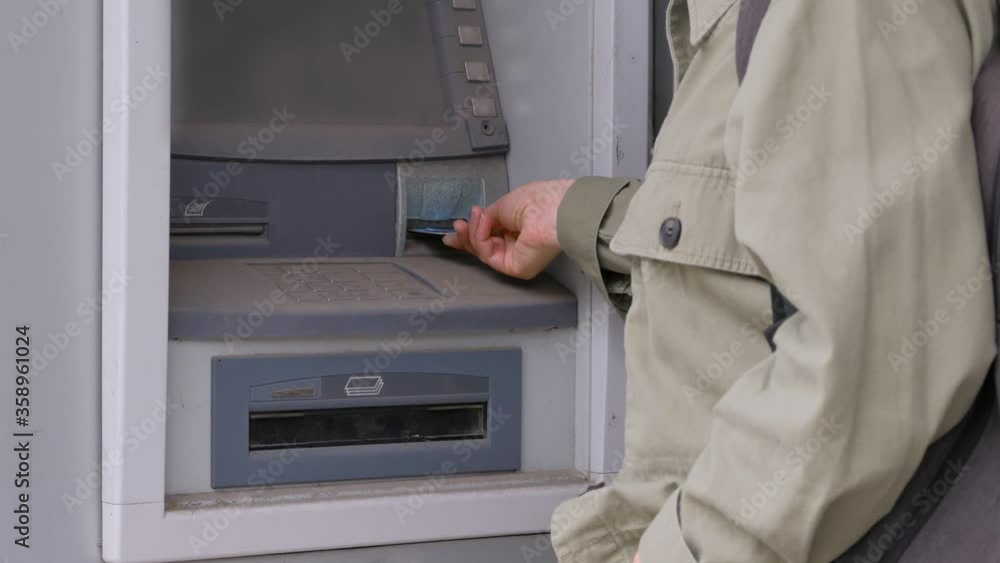The woman unsuccessfully enters the pin code into the damaged ATM. The woman unsuccessfully enters the pin code into the damaged ATM.