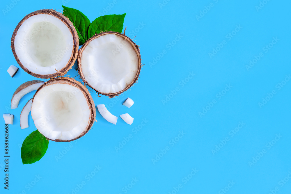 Coconut halves, shavings, green leaves are in left corner of blue background. Summer tropical exotic fruits for cooking alternative milk. Natural healthy organic vegan vegetarian meal food concept. Coconut halves, shavings, green leaves are in left corner of blue background. Summer tropical exotic fruits for cooking alternative milk. Natural healthy organic vegan vegetarian meal food concept.