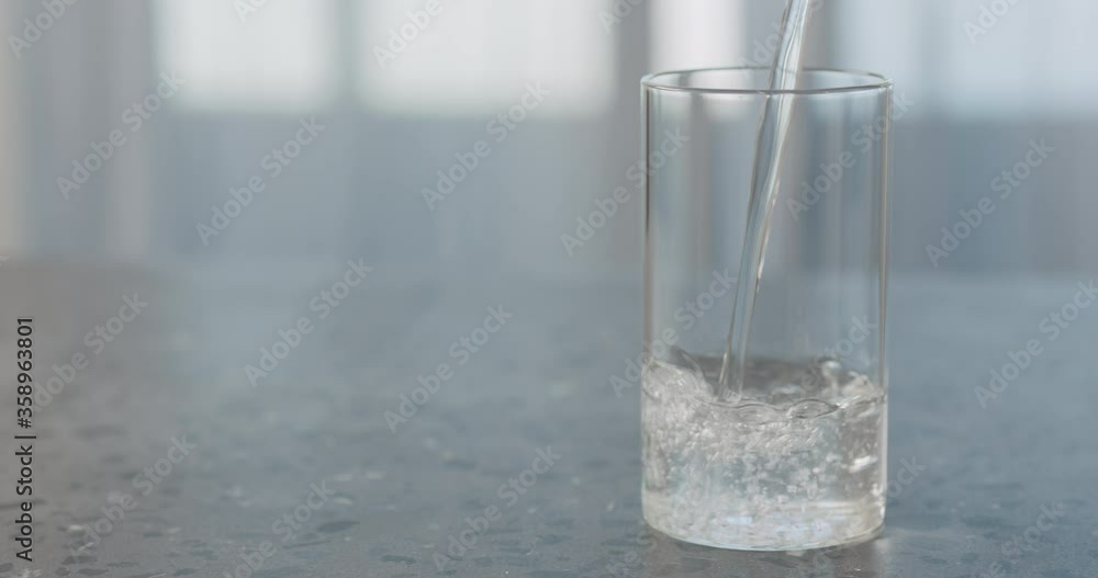 Slow motion water pour into glass on concrete background with copy space Slow motion water pour into glass on concrete background with copy space