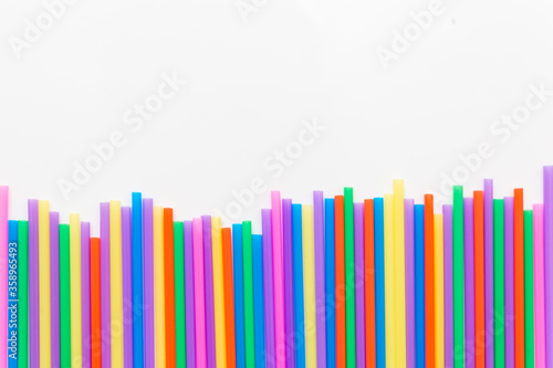 A strip of many plastic colored straws arranged in a row. Isolated