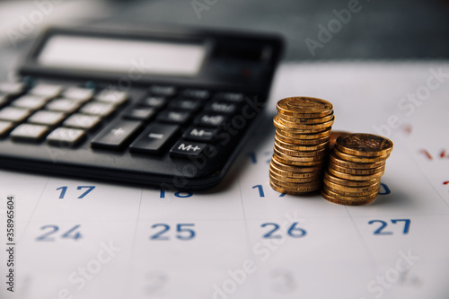 Calendar, calculator and stack of coins in a office. photo