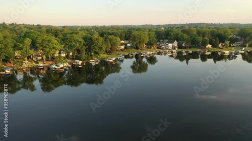 Aerial view of american suburb at summertime.  Establishing shot of american neighborhood. Real estate, residential houses with boat launch on the lake shore. Drone shot, from above, sunrise, morning photo