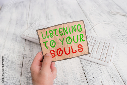 Conceptual hand writing showing Listening To Your Souls. Concept meaning Meditation Follow your conscience Conscientious Man holding colorful reminder square shaped paper wood floor