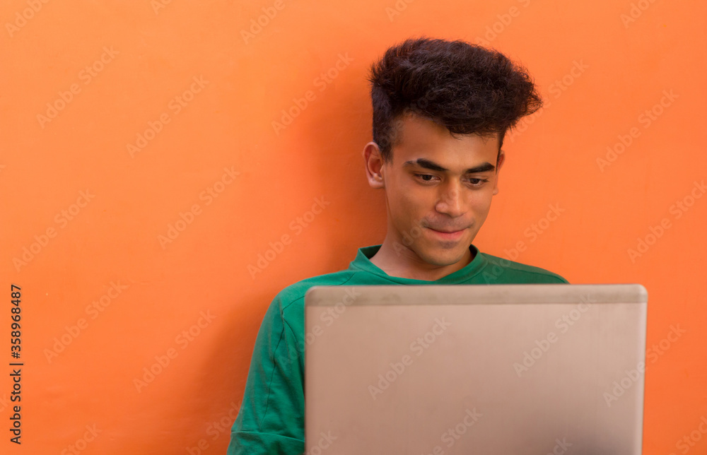 A Young Man smiling while talking to someone on a video call on his laptop. A Young Man smiling while talking to someone on a video call on his laptop.