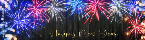 HAPPY NEW YEAR background panorama - Firework in the colors from the flag of united states of america isolated on dark rustic wooden wall texture, with space for text