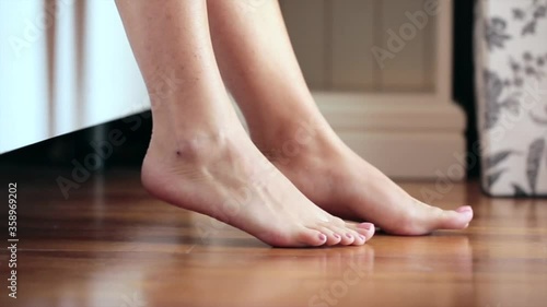 Woman aplying footcream on her legs in the morning after getting out of the bed photo