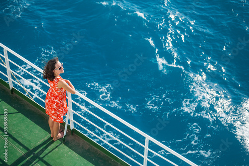 A girl is standing near the fence on a ship and looking at the sea, view from above