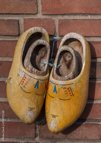 Close-up of adult and childerens's dutch wooden clogs hanging on a stone wall