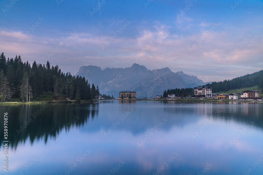 Obraz premium Reflection of seamless calm and still lake in Misurina, Italy with yellow building in front of mountains