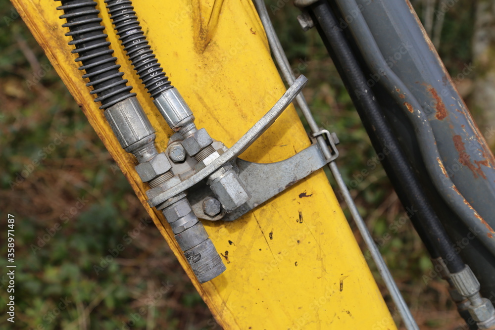 A closeup view of the hydraulic arm on a yellow excavator. A closeup view of the hydraulic arm on a yellow excavator.