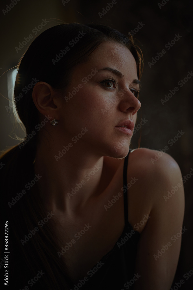 Creative portrait of a photo shoot using smoke a young beautiful girl with brown hair light falls on her hair Creative portrait of a photo shoot using smoke a young beautiful girl with brown hair light falls on her hair
