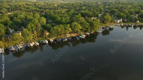 Aerial view of american suburb at summertime.  Establishing shot of american neighborhood. Real estate, residential houses with boat launch on the lake shore. Drone shot, from above, sunrise, morning photo