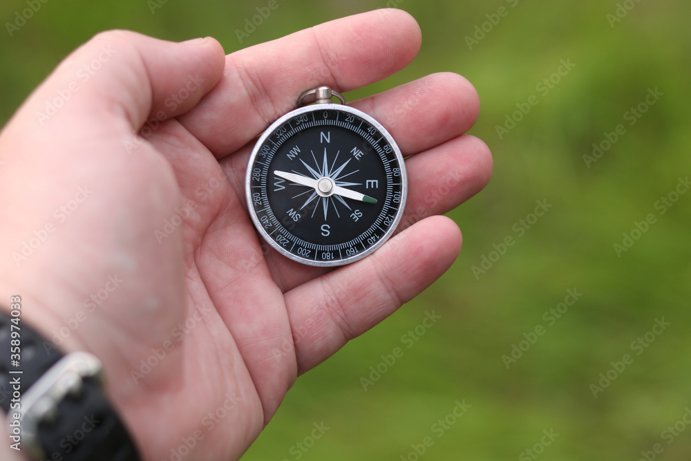Old classic navigation compass in hand on natural background Old classic navigation compass in hand on natural background