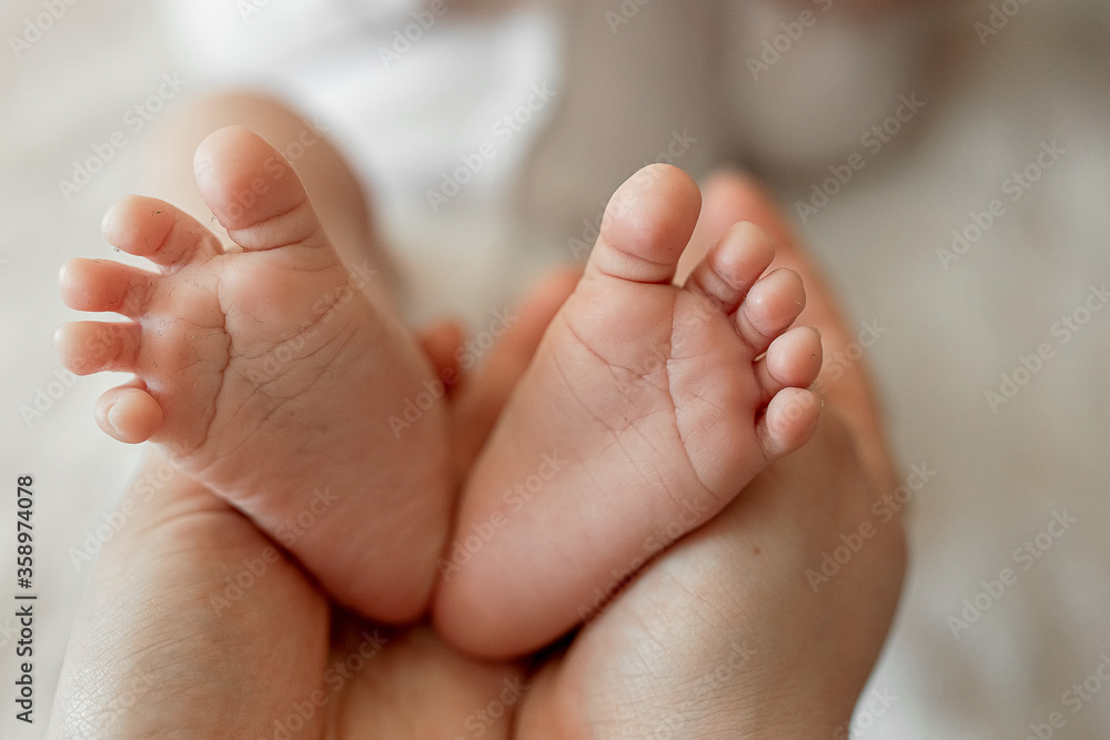 Small baby feet of a baby in the hands of the mother. Love in the family. Family value. A mother's love for a newborn child. The concept of a happy childhood. Small baby feet of a baby in the hands of the mother. Love in the family. Family value. A mother's love for a newborn child. The concept of a happy childhood.