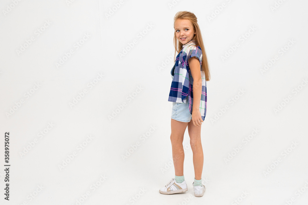 girl in a casual look stands sideways and poses on a white background with copy space girl in a casual look stands sideways and poses on a white background with copy space