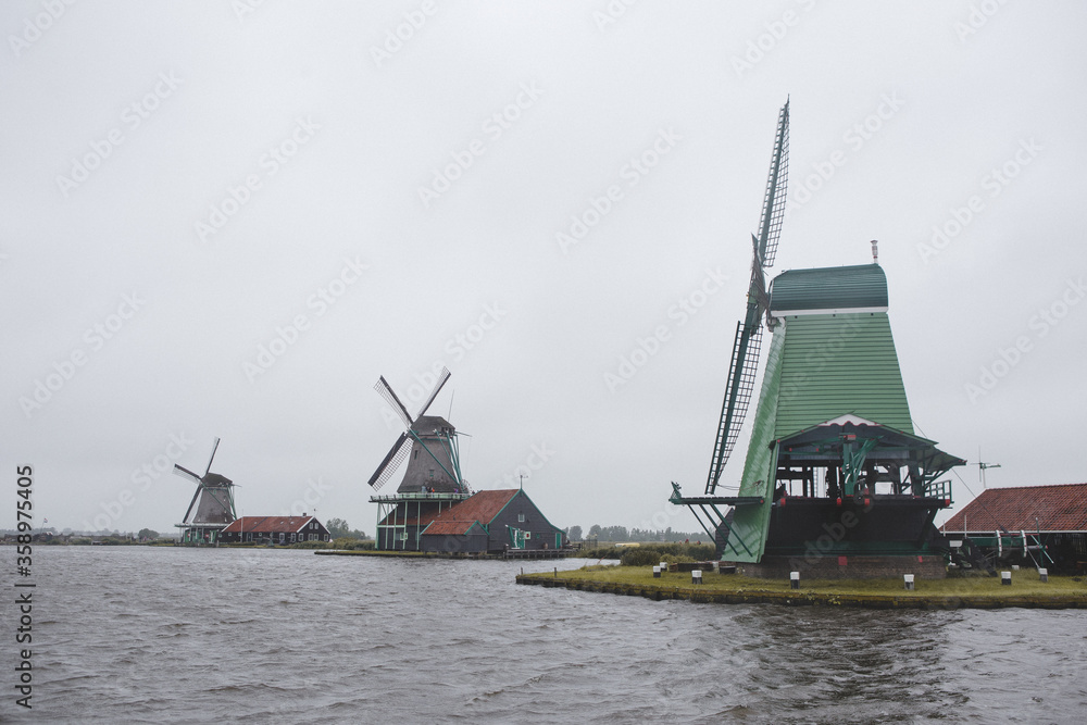 Windmills in Zaanse Schans village, near the sea coast, on a cloudy day.